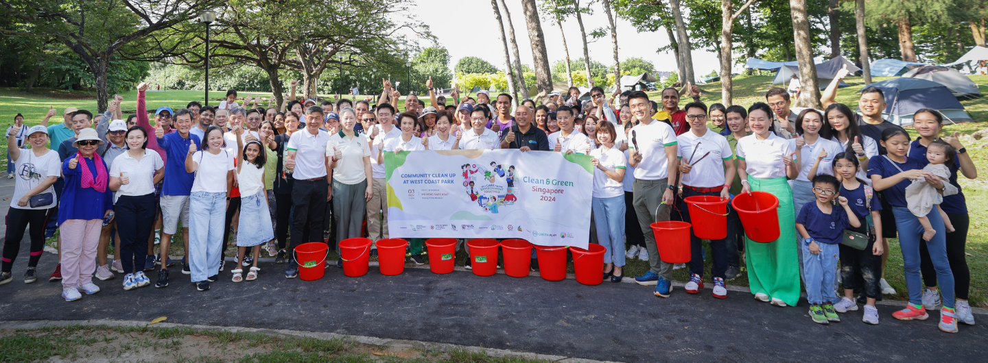 Group of people with red buckets holding "Clean & Green Singapore 2024" banner.